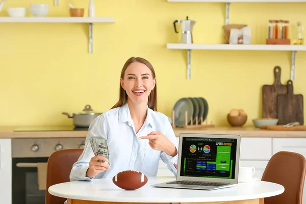 Beautiful woman placing sports bet in kitchen
