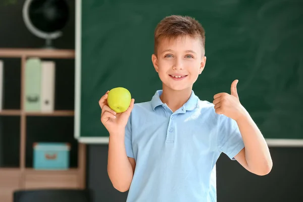 Schoolboy with apple against blurred background in school