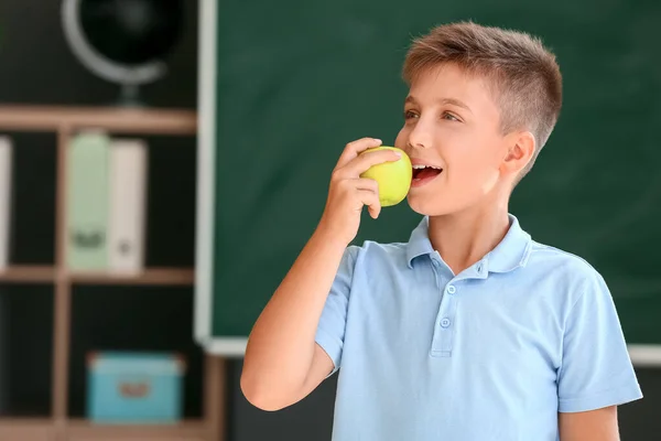 Schoolboy Comer Maçã Contra Fundo Turvo Escola — Fotografia de Stock