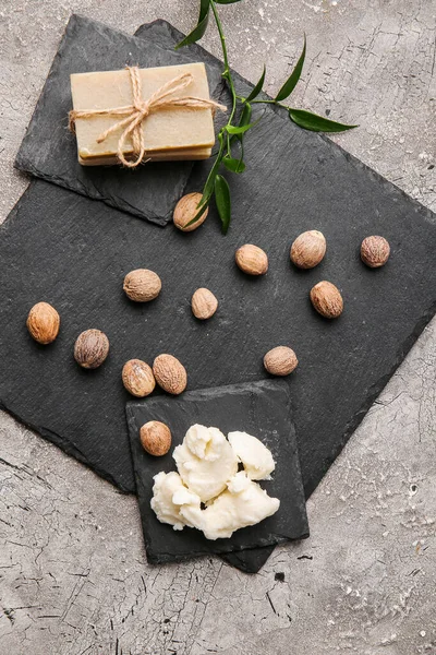 Shea butter with soap and nuts on grunge background