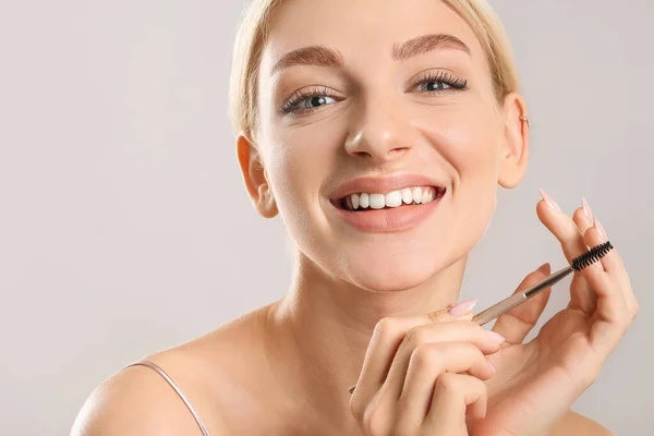 Young Woman Correcting Her Eyebrows Grey Background — Stock Photo, Image