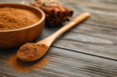 Ahşap zemin üzerinde tarçın tozu olan kase ve kaşık