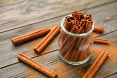 Ahşap arka planda kavanozda tarçın çubukları