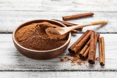 Tarçın çubukları ve tahta zemin üzerinde toz olan kase.