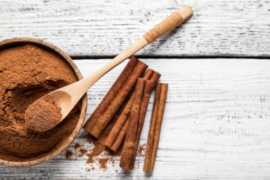 Tarçın çubukları ve tahta zemin üzerinde toz olan kase.