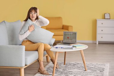 Evde son teslim tarihine yetişmeye çalışan stresli genç bir kadın.