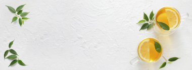 Beyaz zemin üzerinde limon ve yeşil çay yaprakları ile sıcak aromatik çay fincanları metin için yer ile