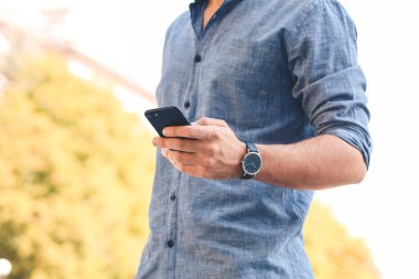 Dışarıda şık kol saati ve cep telefonu olan yakışıklı bir adam.