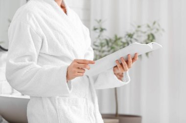 Banyoda boş dergi okuyan genç bir kadın.