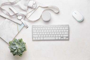 Kol saati, cihazlar ve hafif arka planda ev bitkisi olan şık bir kompozisyon.