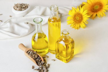 Yağ şişeleri, çekirdekli kepçeler ve ışık arka planında ayçiçekleri