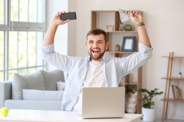 Evdeki spor bahsini kazandıktan sonra cep telefonu ve parası olan mutlu bir adam.