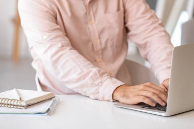 Evde dizüstü bilgisayarda çalışan genç adam, yakın plan.