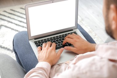 Evde dizüstü bilgisayarda çalışan genç adam.