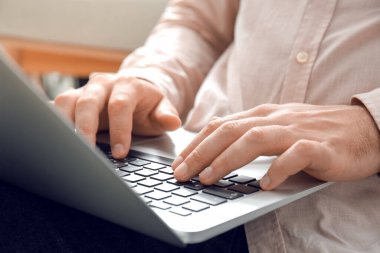 Evde dizüstü bilgisayarda çalışan genç adam, yakın plan.