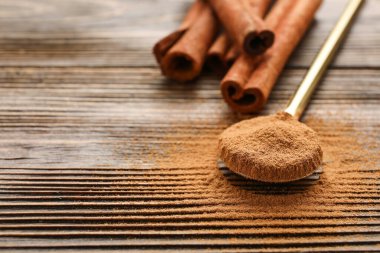 Tarçın çubukları ve tahta zemin üzerinde toz olan kaşık.