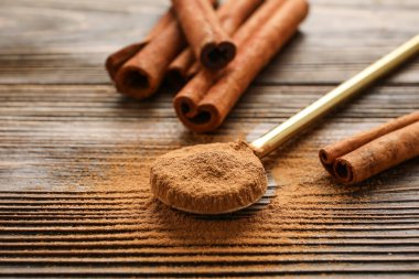 Tarçın çubukları ve tahta zemin üzerinde toz olan kaşık.