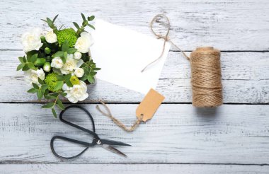 Bir buket güzel çiçek ve beyaz ahşap arka planda boş kart.