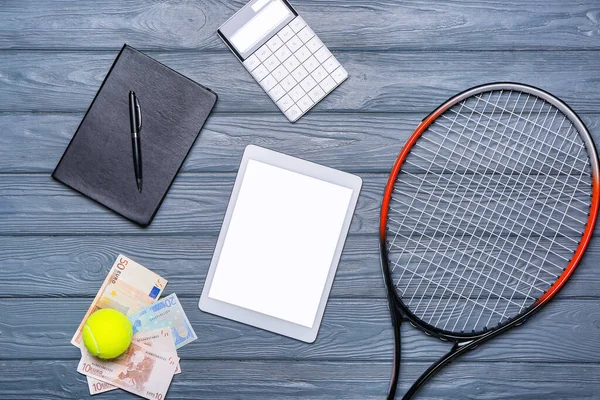 Tablet computer, money and notebook on dark wooden background. Concept of sports bet