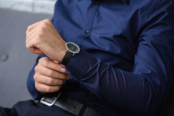 Молодой бизнесмен с наручными часами в офисе, крупным планом