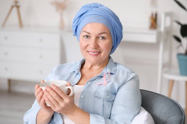 Kemoterapiden sonra evde çay içen olgun bir kadın.