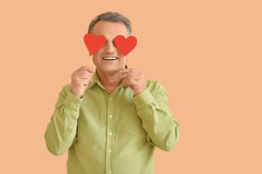 Renkli arka planda kırmızı kalpli olgun bir adam.