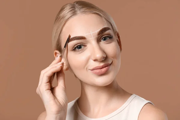 Mujer Joven Corrigiendo Sus Cejas Contra Fondo Color — Foto de Stock