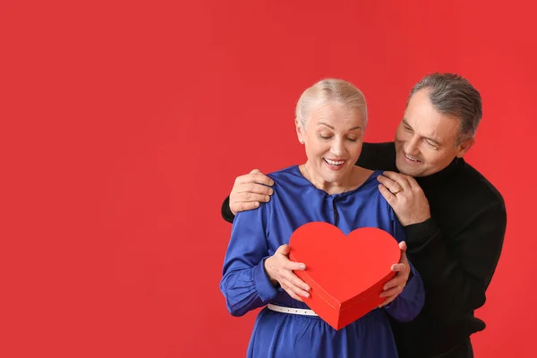 Pareja Madura Con Regalo Sobre Fondo Color Celebración San Valentín —  Fotos de Stock