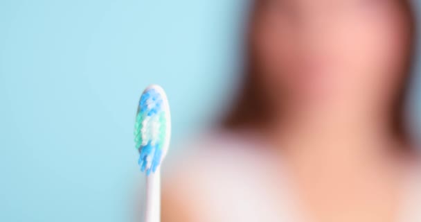 色の背景に美しい笑顔と歯ブラシを持つ若い女性 — ストック動画