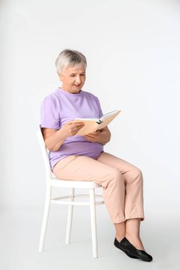 Üst düzey kadın beyaz arka plan üzerine kitap okuyor.