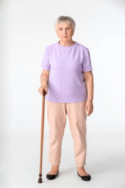 Beyaz arka planda bastonu olan son sınıf öğrencisi bir kadın.