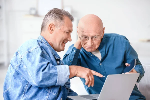 Oudere Mensen Met Verschillende Apparaten Zitten Bank Thuis — Stockfoto