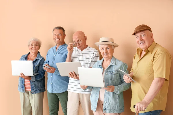 Senior people with different devices near color wall in room