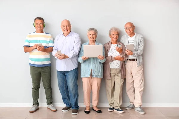 Пожилые Люди Различными Устройствами Возле Светлой Стены Комнате — стоковое фото