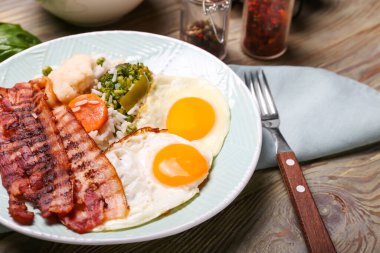 Lezzetli yumurta, domuz pastırması ve ahşap kaplama pirinç tabağı.