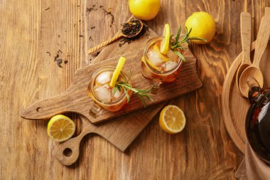 Ahşap arka planda limonlu soğuk siyah çay kavanozları.