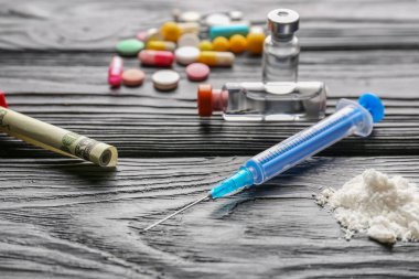 Şırınga, uyuşturucu ve para ahşap arka planda