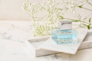 Açık arkaplanda bir şişe çiçek parfümü.