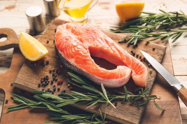 Ahşap arka planda çiğ somon bifteği ve limon.