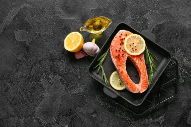 Koyu arkaplanda çiğ somon bifteği ve limon