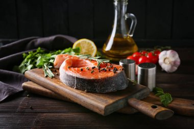 Çiğ somon bifteği, baharatlar ve ahşap arka planda otlar.