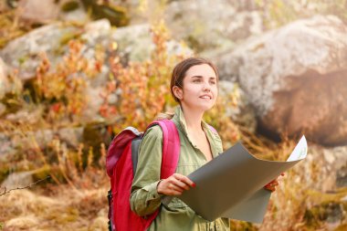 Dağlarda haritası olan genç bir bayan turist.