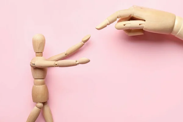 Wooden mannequin and hand on color background