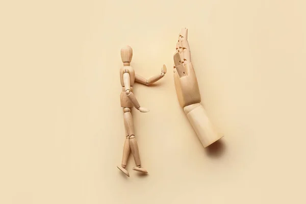 Wooden mannequin and hand on color background