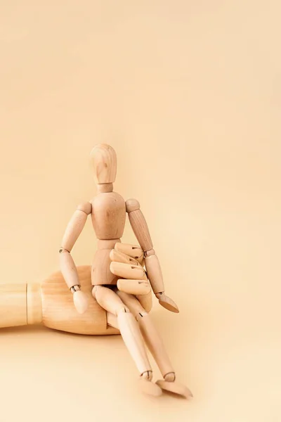 Wooden mannequin and hand on color background