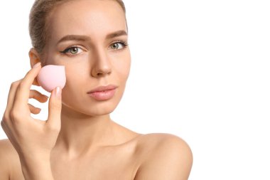 Beyaz arka planda makyaj süngeri olan güzel bir genç kadın.