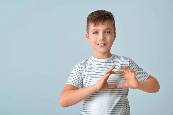 Schattig Jongetje Maken Hart Met Haar Handen Grijze Achtergrond — Stockfoto