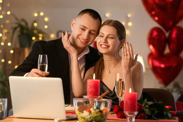 Happy engaged couple video chatting with friends on Valentine\'s Day at home