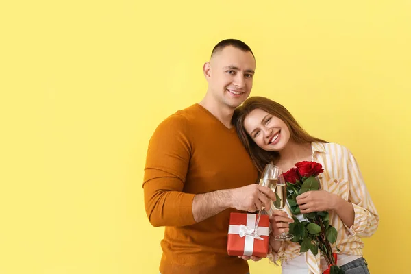 Casal Jovem Com Copos Champanhe Presente Flores Fundo Cor Celebração — Fotografia de Stock