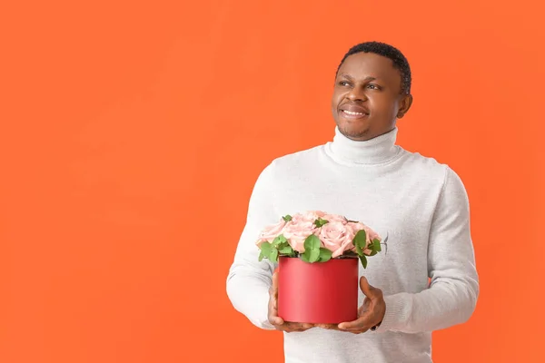 stock image African-American man with flowers on color background. Valentine's Day celebration